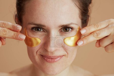 Téléchargez les photos : Portrait de femme souriante moderne de 40 ans avec des bandeaux isolés sur fond beige. - en image libre de droit