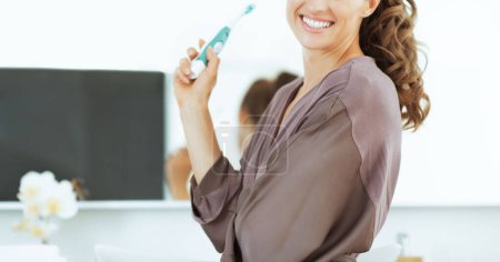 Téléchargez les photos : Joyeux jeune femme brossant les dents dans la salle de bain - en image libre de droit