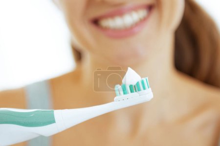 Téléchargez les photos : Gros plan sur une jeune femme montrant une brosse à dents électrique - en image libre de droit