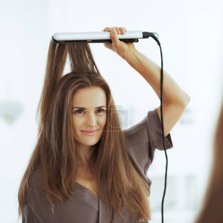 Foto de Mujer alisando el cabello con alisador - Imagen libre de derechos