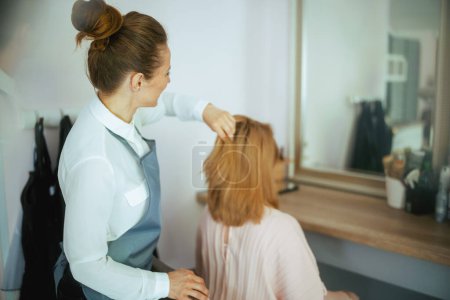 Photo for Seen from behind woman hairdresser in modern hair studio with client. - Royalty Free Image