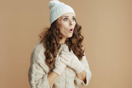 Photo for Hello winter. surprised modern woman in beige sweater, mittens and hat isolated on beige. - Royalty Free Image