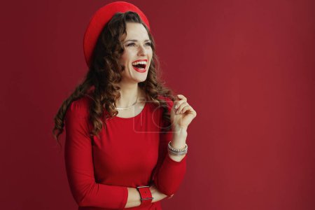 Foto de Feliz San Valentín. mujer elegante sonriente con el pelo ondulado largo en vestido rojo y boina sobre fondo rojo. - Imagen libre de derechos