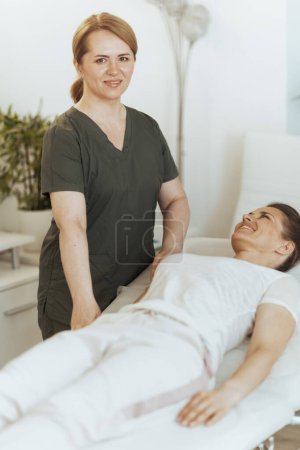 Téléchargez les photos : Temps de santé. souriant massothérapeute féminine dans l'armoire de massage avec le client faisant check-up. - en image libre de droit