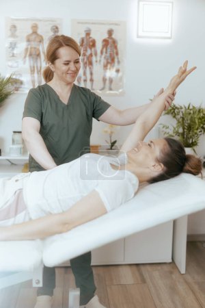 Foto de Tiempo de atención médica. terapeuta de masaje femenino sonriente en gabinete de masaje con cliente haciendo chequeo. - Imagen libre de derechos
