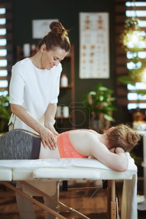 Téléchargez les photos : Temps de santé. massothérapeute femme dans l'armoire de massage avec adolescent client faisant massage sur table de massage. - en image libre de droit