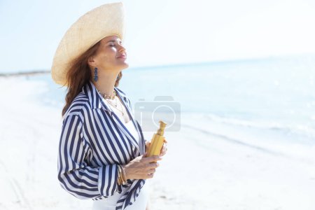 Foto de Sonriente hembra elegante en la costa con protector solar. - Imagen libre de derechos