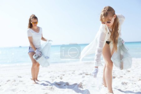 Téléchargez les photos : Bénévoles féminines concernées sur le rivage de l'océan avec des sacs poubelle collecte des ordures. - en image libre de droit