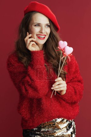 Photo for Happy Valentine. smiling trendy 40 years old woman in red sweater and beret with hearts on stick. - Royalty Free Image