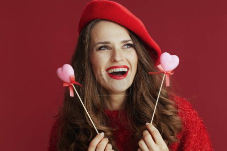 Téléchargez les photos : Joyeux Valentin. heureux élégant femelle en pull rouge et béret avec des coeurs sur le bâton. - en image libre de droit