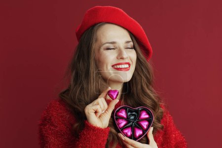 Photo for Happy Valentine. relaxed stylish middle aged woman in red sweater and beret with heart shaped candy box. - Royalty Free Image
