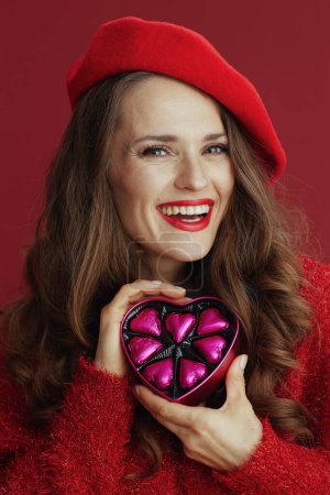 Téléchargez les photos : Joyeux Valentin. heureuse femme moderne en pull rouge et béret avec boîte à bonbons en forme de coeur. - en image libre de droit