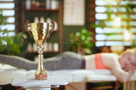 Photo for Healthcare time. Closeup on trophy cup and teenage girl in medical massage therapist cabinet in background. - Royalty Free Image