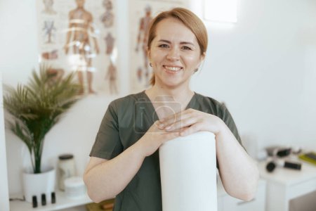 Photo for Healthcare time. Portrait of happy massage therapist woman in massage cabinet with disposable sheet preparing for new client. - Royalty Free Image