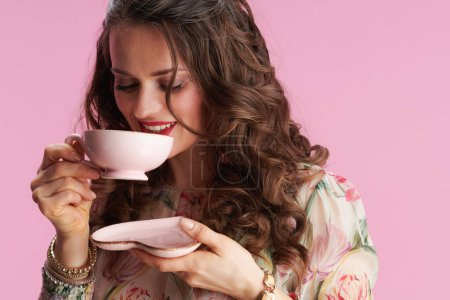 Foto de Feliz mujer elegante con el pelo largo y ondulado morena con taza de té aislado sobre fondo rosa. - Imagen libre de derechos