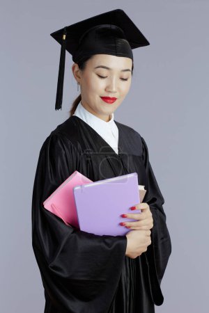 Photo for Pensive modern graduate student asian woman with books and notebooks isolated on gray background. - Royalty Free Image