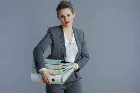 Téléchargez les photos : Élégante femme d'affaires de 40 ans en costume gris avec des dossiers isolés sur fond gris. - en image libre de droit