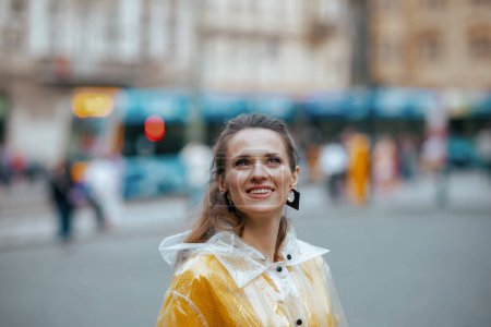 Photo for Surprised stylish solo tourist woman in yellow blouse and raincoat in Prague Czech Republic on tram station and walking. - Royalty Free Image