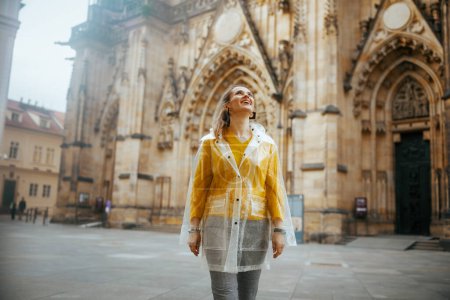 Téléchargez les photos : Surprise femme touristique tendance en chemisier jaune et imperméable à Prague République tchèque explorer les attractions. - en image libre de droit