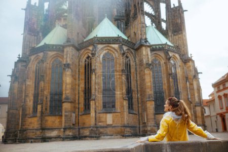 Téléchargez les photos : Vu de derrière voyageuse solitaire en chemisier jaune et imperméable à Prague République tchèque explorer les attractions. - en image libre de droit