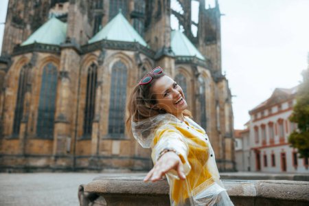 Photo for Happy stylish solo tourist woman in yellow blouse and raincoat in Prague Czech Republic sightseeing. - Royalty Free Image