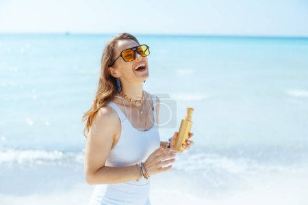Photo for Happy modern 40 years old woman on the ocean coast with sunscreen. - Royalty Free Image