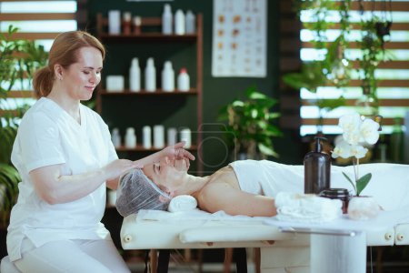 Foto de Tiempo de atención médica. masajista en el salón de spa masajeando a los clientes cara en la mesa de masaje. - Imagen libre de derechos