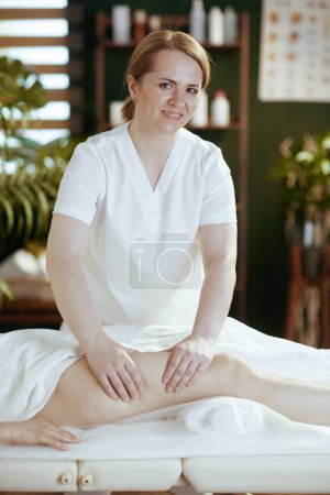Photo for Healthcare time. massage therapist in massage cabinet massaging clients leg on massage table. - Royalty Free Image