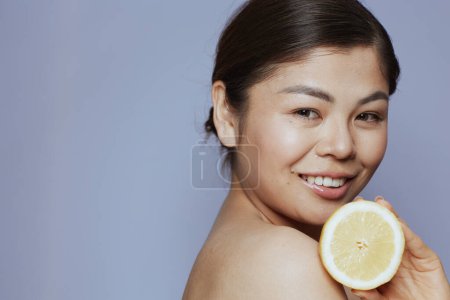 Photo for Portrait of young asian woman with lemon against blue background. - Royalty Free Image