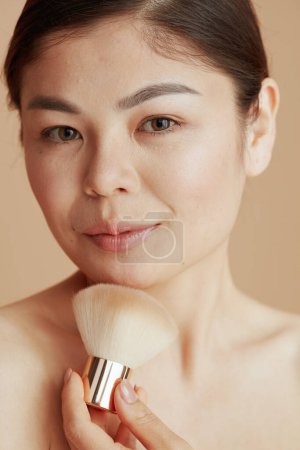 Foto de Retrato de mujer moderna con cepillo de maquillaje sobre fondo beige. - Imagen libre de derechos