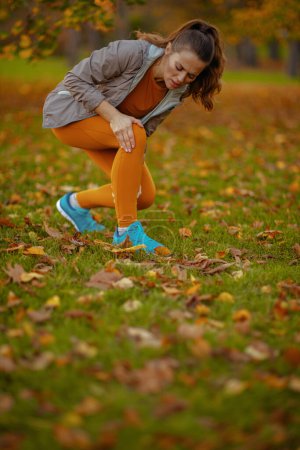 Photo for Hello autumn. sad modern woman in fitness clothes in the park got a leg injury. - Royalty Free Image