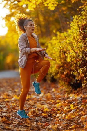 Foto de Hola otoño. Retrato de longitud completa de la mujer con estilo en ropa de fitness en el entrenamiento del parque. - Imagen libre de derechos