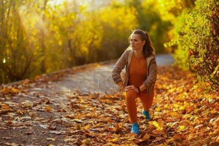 Foto de Hola otoño. mujer de mediana edad en ropa de fitness en el parque estiramiento. - Imagen libre de derechos