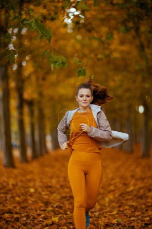 Téléchargez les photos : Bonjour l'automne. élégante femme en vêtements de fitness dans le parc de jogging. - en image libre de droit