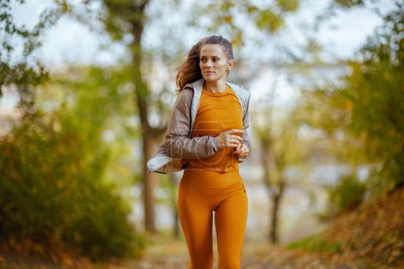 Photo for Hello autumn. stylish female in fitness clothes in the park jogging. - Royalty Free Image