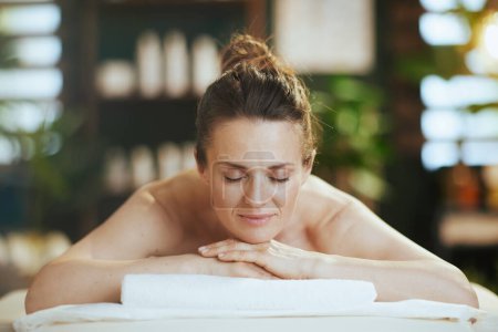 Temps de santé. femme moderne détendue dans le salon de spa pose sur la table de massage.