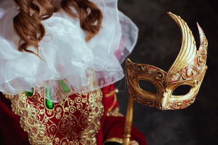 Téléchargez les photos : Gros plan sur la reine médiévale en robe rouge avec masque vénitien et col blanc. - en image libre de droit