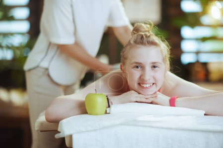 Téléchargez les photos : Temps de santé. femme massothérapeute médicale dans une armoire de massage avec un client adolescent et une pomme faisant massage sur table de massage. - en image libre de droit