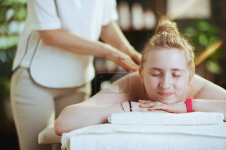 Temps de santé. massothérapeute féminine dans une armoire de massage avec un client adolescent faisant un massage sur une table de massage.