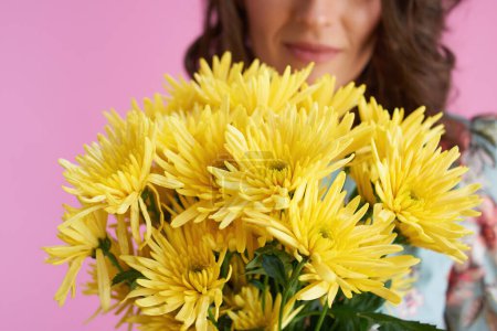 Foto de Primer plano femenino con flores de crisantemos amarillos sobre fondo rosa. - Imagen libre de derechos