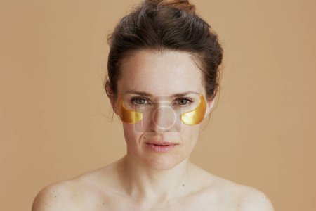 Téléchargez les photos : Portrait de femme moderne de 40 ans avec des bandeaux isolés sur fond beige. - en image libre de droit