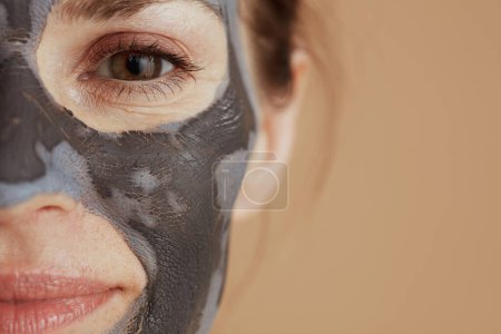 Foto de Primeros planos de una mujer de 40 años con máscara facial sobre fondo beige. - Imagen libre de derechos