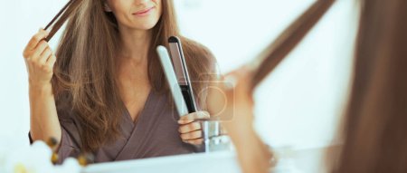 Photo for Happy young woman checking hair after straightening - Royalty Free Image