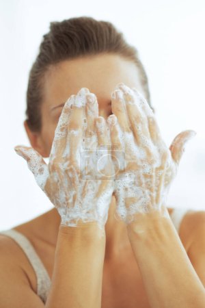 Téléchargez les photos : Jeune femme lavage visage dans la salle de bain - en image libre de droit