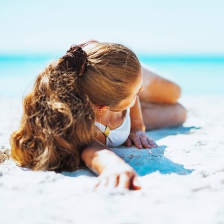 Junge Frau im Badeanzug am Strand liegend. Rückansicht