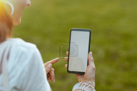 Foto de Hora de verano. Primer plano femenino con smartphone y pantalla en blanco en el prado exterior en la naturaleza. - Imagen libre de derechos