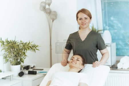 Foto de Tiempo de atención médica. terapeuta de masaje médico femenino sonriente en gabinete de masaje con cliente. - Imagen libre de derechos