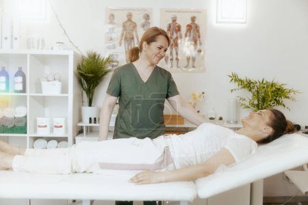 Téléchargez les photos : Temps de santé. souriant massothérapeute femme dans l'armoire de massage avec client faisant check-up. - en image libre de droit