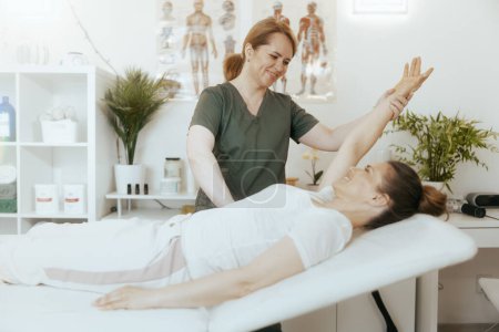 Foto de Tiempo de atención médica. terapeuta de masaje médico mujer feliz en el gabinete de masaje con el cliente realizando el examen. - Imagen libre de derechos
