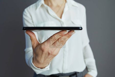 Closeup on woman employee in white blouse with smartphone isolated on grey.